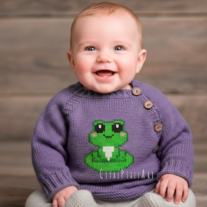 Puede incluir: Un suéter de punto morado de manga larga con un gráfico de rana verde en la parte delantera. El suéter tiene un cuello redondo y tres botones de madera marrón a lo largo de la costura del hombro izquierdo. El texto CitriPixelArt es visible.