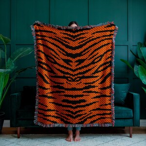May include: A large orange and black tiger-striped woven throw blanket with fringed edges.
