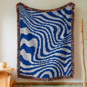 May include: A blue and white woven throw blanket with a wavy pattern. The blanket has a fringe border.