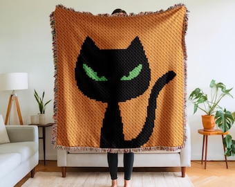 May include: An orange throw blanket with a black cat design and green eyes. The blanket has a textured pattern and fringed edges. The cat's silhouette is prominent against the orange background, creating a Halloween theme. The blanket is suitable for a sofa.