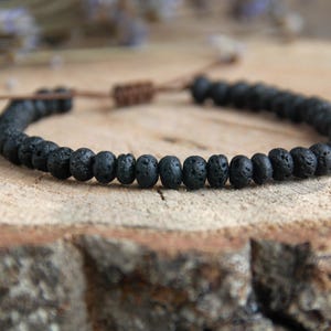Peut inclure: Un bracelet en perles de roche volcanique noire avec une fermeture en cordon marron.