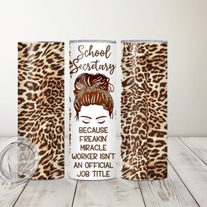May include: White tumbler with a leopard print design on the sides. The front of the tumbler features a cartoon illustration of a woman with a messy bun and the text "School Secretary because freakin' miracle worker isn't an official job title."