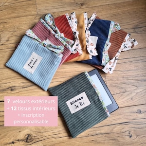 Peut inclure: Sept housses en tissu de différentes couleurs pour une liseuse. Les housses sont en velours côtelé et ont un motif floral à l'intérieur. Les housses portent des textes différents, dont "Chut ! Je rêve" et "Silence Je lis".