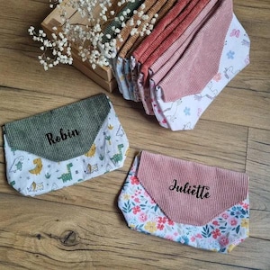 May include: A collection of envelope-style pouches featuring corduroy flaps in various colors and patterned fabric bodies. Two pouches are displayed in the foreground, one with a green flap labeled Robin and one with a pink flap labeled Juliette.