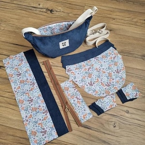 Puede incluir: Un conjunto de piezas de tela para un proyecto de bricolaje, que incluye una bolsa de pana azul con la palabra "LOVE" en ella, una cremallera y varias piezas de tela con un patrón floral.