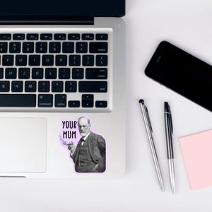 Puede incluir: Una pegatina con una imagen en blanco y negro de Sigmund Freud con un cigarrillo en la mano. La pegatina tiene el texto "YOUR MUM" en letras negras sobre un fondo morado.
