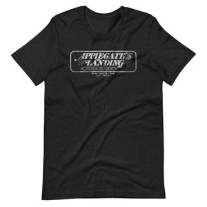 Puede incluir: Camiseta negra con un logotipo blanco de estilo vintage que dice "Applegate's Landing Pizza & More Wichita, KS Est. 1973"
