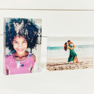 May include: Two rectangular photo blocks. One features a smiling girl in a pink top, the other shows a couple dancing on a beach. The blocks are clear and stand upright.
