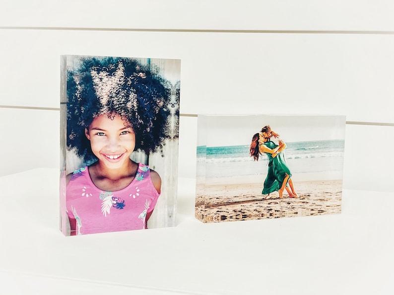 May include: Two rectangular photo blocks. One features a smiling girl in a pink top, the other shows a couple dancing on a beach. The blocks are clear and stand upright.