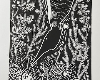 May include: Black and white linocut print of a loon diving underwater with fish. The print is titled "Loon Diving" and signed "B. Carlson 21'" with the number "3/25" in the bottom left corner.