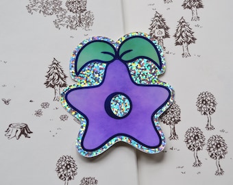 Può includere: Un adesivo a forma di stella viola con uno stelo e foglie verdi. L'adesivo ha una finitura olografica e un contorno bianco.