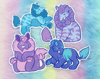 May include: Four die-cut stickers featuring stylized fantasy creatures with fur and tails. One is light blue with stripes, one is purple and lavender with curly fur, one is dark purple with pink accents, and one is dark blue with teal spots.
