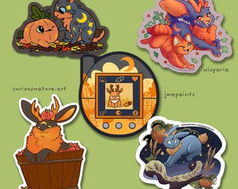 May include: A collection of five stickers featuring illustrated creatures and a digital pet device. Designs include a rabbit with a pumpkin, a rabbit and cat, a rabbit in an apple barrel, a blue rabbit, and a digital pet device with a deer icon.
