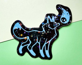 May include: A die-cut sticker featuring a black wolf silhouette filled with a holographic star pattern. The wolf has light blue outlines and a light blue tail tip. A light blue flame-like shape with a skull icon floats above the wolf's tail.