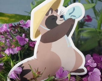 May include: A die-cut sticker featuring a tan and brown raccoon wearing a yellow conical hat. The raccoon is holding a light blue bottle to its mouth with both paws. The illustration has a white border and a smooth, matte-style finish.