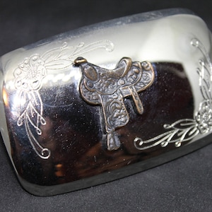 Vintage silver rectangular belt buckle.  Engraved flower and leaves in two corners as well as a centre bronze/black saddle medallion.