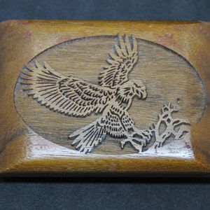 Vintage wodden rectangular shaped belt buckle. Engraved design features an eagle landing on a branch. Medium brown colour with gold findings