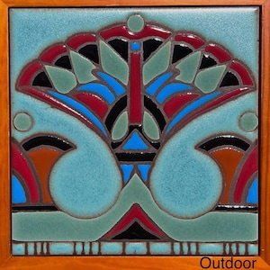 Puede incluir: Un azulejo de cerámica con un diseño geométrico en tonos de azul, verde, rojo, negro y marrón. El azulejo está enmarcado en madera y tiene la palabra "Outdoor" impresa en la esquina inferior derecha.