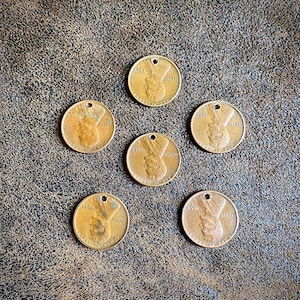 May include: Six antique gold-colored metal tokens with a hole at the top. Each token has a raised image of a person's face and the text "5&cent;&cent;1" and "ALBERTI" on the front.