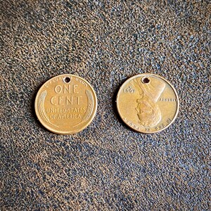 May include: Two copper US one cent coins. The obverse side features the words "One Cent" and "United States of America". The reverse side features a profile of Abraham Lincoln and the words "In God We Trust" and "Liberty".