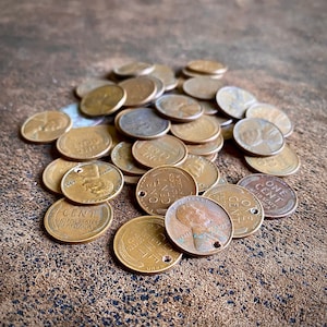 May include: A pile of copper US one-cent coins, also known as pennies, with the words "ONE CENT" and "UNITED STATES OF AMERICA" visible on some of the coins.