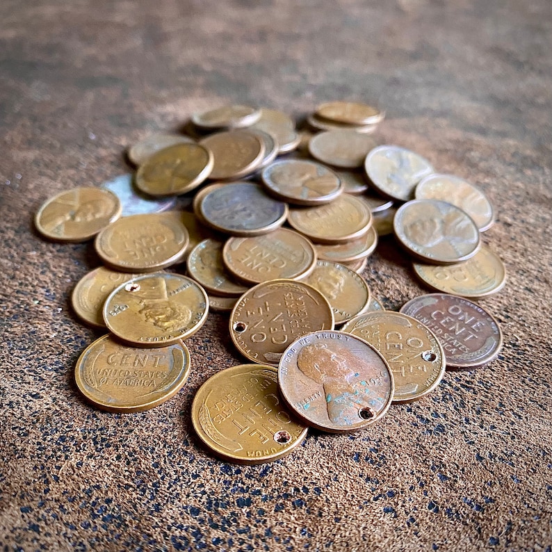 May include: A pile of copper US one-cent coins, also known as pennies, with the words "ONE CENT" and "UNITED STATES OF AMERICA" visible on some of the coins.
