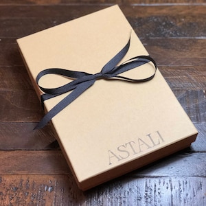May include: A brown cardboard box with a black ribbon tied around it. The box is labeled "ASTALI".