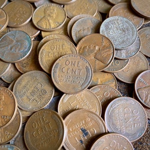 May include: A close-up image of a pile of copper US one-cent coins. The coins are from different years and have the words "One Cent" and "United States of America" inscribed on them.