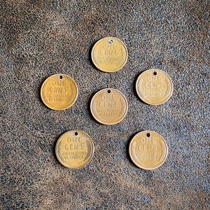 May include: Six antique copper-colored US one-cent coins with the words "One Cent" and "United States of America" on each coin.
