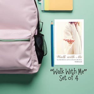 May include: A light pink backpack with a black handle and mesh side pockets sits next to a set of notebooks and a blue pencil. A card with the text "Walk With Me" and a picture of a person in a white robe is also present.