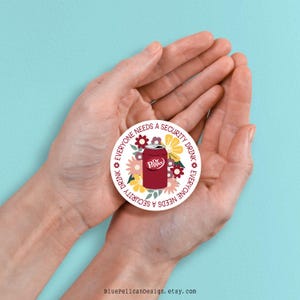 May include: A round sticker with a white background and a red Dr Pepper can surrounded by colorful flowers. The text around the can reads "Everyone needs a security drink" in a circular pattern.