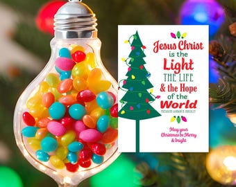 May include: A Christmas card with a green Christmas tree decorated with colorful lights. The card features the text "Jesus Christ is the Light THE LIFE & the Hope of the World" and "May your Christmas be Merry & bright".