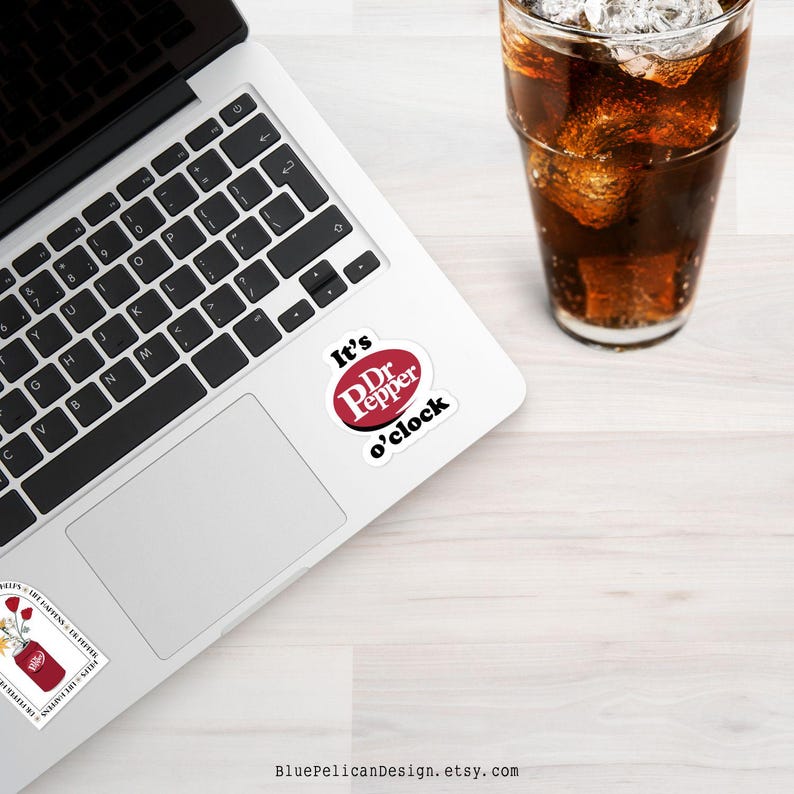 May include: A white laptop with a black keyboard and a Dr Pepper sticker on the top right corner of the trackpad. The sticker says "It's Dr Pepper o'clock".