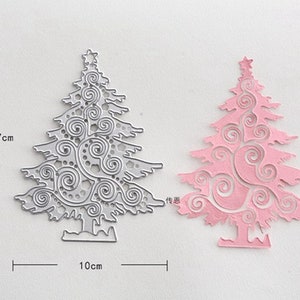 Puede incluir: Una troquelada de metal de un &aacute;rbol de Navidad con un dise&ntilde;o de espiral. La troquelada mide 7,7 cm de alto y 10 cm de ancho. Se muestra una troquelada de papel rosa del mismo dise&ntilde;o junto a la troquelada de metal.
