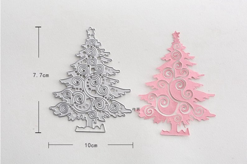 Puede incluir: Una troquelada de metal de un &aacute;rbol de Navidad con un dise&ntilde;o de espiral. La troquelada mide 7,7 cm de alto y 10 cm de ancho. Se muestra una troquelada de papel rosa del mismo dise&ntilde;o junto a la troquelada de metal.