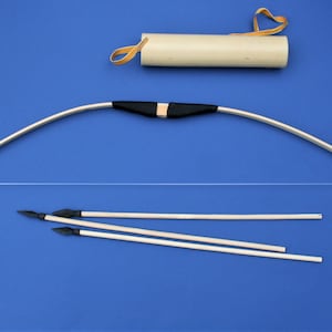 May include: A traditional bow and arrow set, featuring a light-coloured wooden bow with a black grip and white string. The set includes three arrows with black arrowheads and a light tan quiver with a yellow strap. The items are set against a blue backdrop.