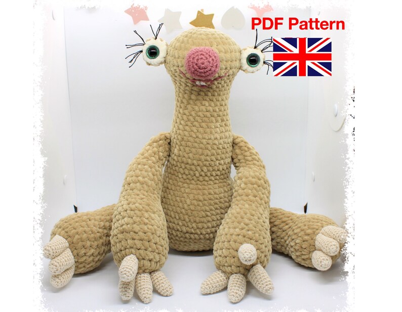 May include: Crochet pattern for a sloth amigurumi toy. The pattern is available as a PDF download. The sloth is beige with a pink nose and green eyes.