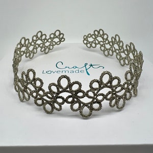 Könnte beinhalten: Ein silbernes Spitzenhaarband mit einem zarten Blumenmuster. Das Haarband liegt auf einem weißen Hintergrund mit dem Text "Craft Lovemade".
