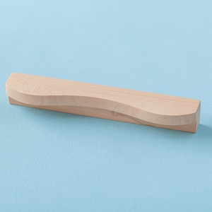May include: A light wood drawer pull with a curved, wave-like design.