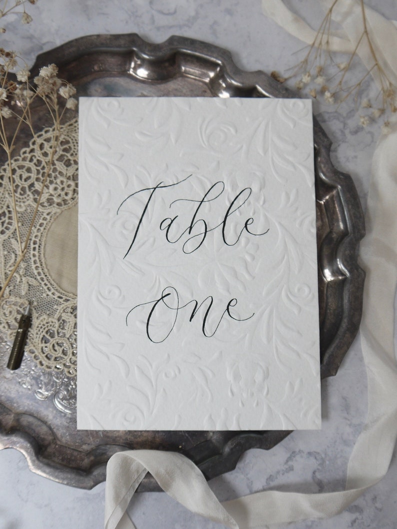 Textured Table Number Signs, Embossed Calligraphy Wedding Table Name Signage, Off White Event Table Decor, Ornate A6 Handwritten Custom Sign image 1