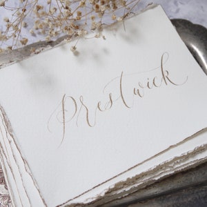 Calligraphy table sign on torn paper for weddings
