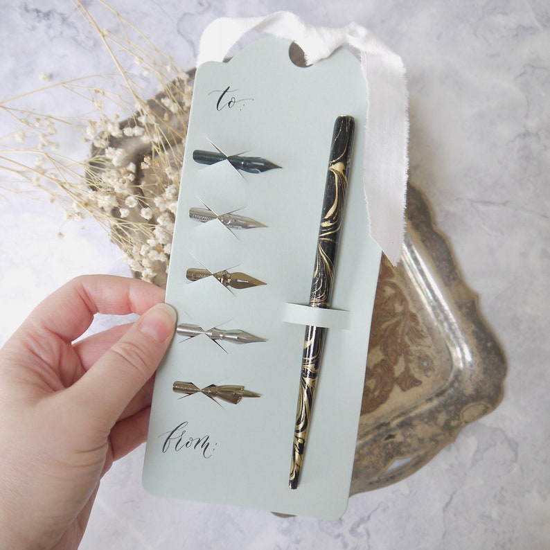 5 calligraphy nibs and a pen holder set on a large gift tag with ribbon and a personalised message