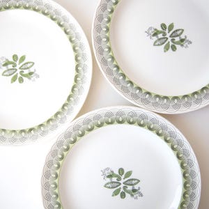 Peut inclure: Trois assiettes en céramique blanche avec une bordure décorative verte et grise et un motif floral central. Les assiettes sont disposées en cercle, mettant en valeur leur design élégant. Idéales pour servir les repas.