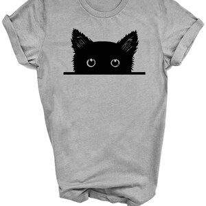 May include: A gray t-shirt with a black silhouette of a cat peeking over the top. The cat's eyes are white.