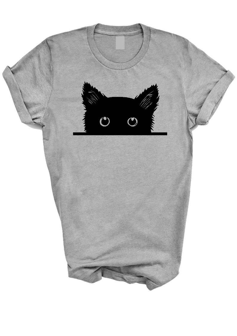May include: A gray t-shirt with a black silhouette of a cat peeking over the top. The cat's eyes are white.