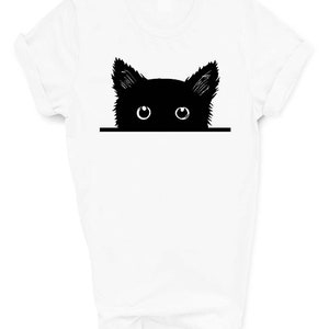 May include: White t-shirt with a black silhouette of a cat peeking over the top with its eyes visible.