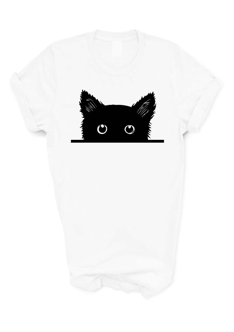 May include: White t-shirt with a black silhouette of a cat peeking over the top with its eyes visible.