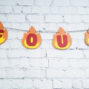 May include: A red and yellow paper banner with the word "FOUR" in red letters. The banner is shaped like flames.