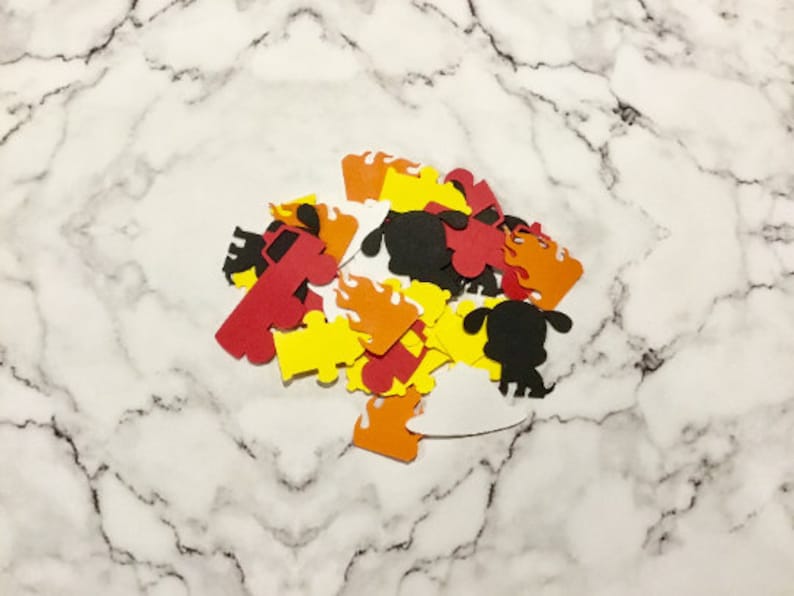 May include: A pile of red, yellow, orange, black, and white paper cutouts of fire trucks, flames, and dogs. The cutouts are on a white marble surface.