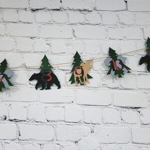 May include: A green and brown woodland-themed banner with cut-out trees, bears, and moose. The banner has the numbers 7, 8, 9, 10, and 11 on it.